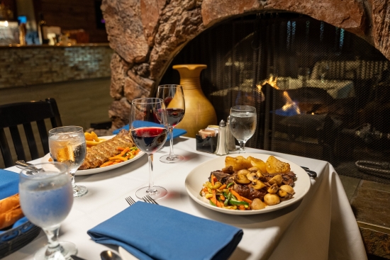 Grilled steak topped with mushrooms, roasted potatoes and vegetables, served with red wine